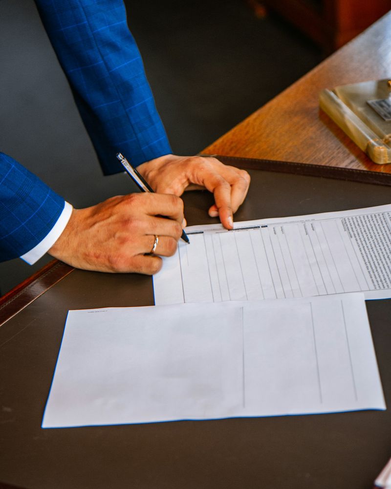 Professionista in abito blu che firma documenti fiscali alla scrivania